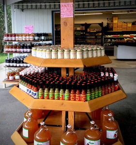 Shelves in a farmer's market lined with jars of Denzel Sanberg's Gourmet Mustards and bottles of Denzel's Hot Sauces.